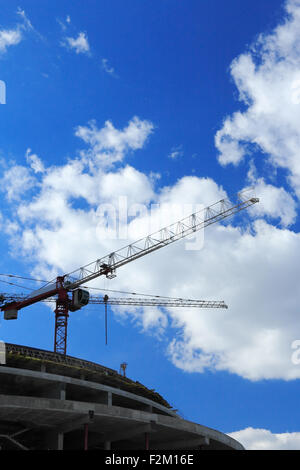 Krane auf Baustelle gegen blauen Himmel und Wolken. Stockfoto