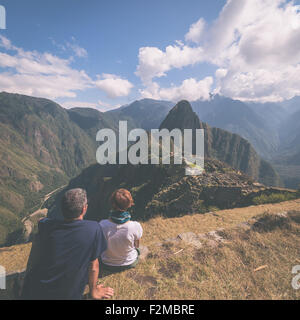 Zwei Menschen sitzen in der Betrachtung auf den Terrassen über Machu Picchu, besuchten der am meisten Reiseziel in Peru. Ansicht von hinten, Stockfoto