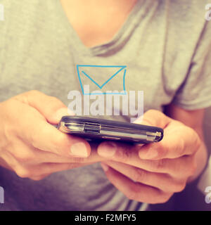 Nahaufnahme eines jungen Mannes in einer Sendung ein oder eine SMS-Nachricht mit seinem Smartphone empfangen Stockfoto