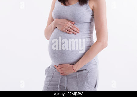 Schwangere Frau streichelt ihren Bauch auf weißem Hintergrund Stockfoto