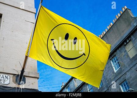 Ein Smiley-Gesicht auf eine gelbe Flagge vor einem blauen Himmel in Edinburgh. Stockfoto