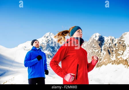 Junges Paar Joggen draußen im sonnigen Winterberge Stockfoto