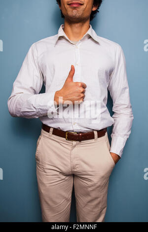 Junger Mann stehend mit einer blauen Wand Daumen aufgeben Stockfoto