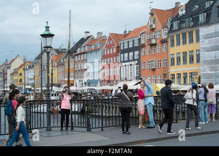 Touristen auf der Kanalbrücke fotografieren und Selfies am Nyhavn, dem neuen Hafen Kopenhagen Dänemark Stockfoto