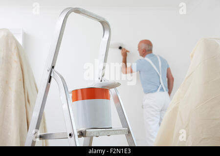 Mann Dekoration Zimmer mit Farbe und Pinsel im Vordergrund Stockfoto