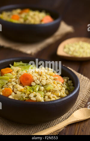 Veganer Eintopf gemacht der Weizenkörner, Wirsing, Karotten, Kürbis und Zwiebel in rustikalen Schüssel Stockfoto