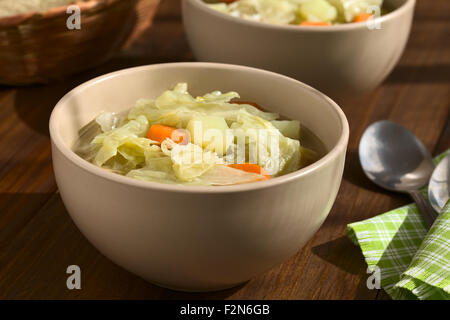 Wirsing, Möhre und Kartoffel-Eintopf oder Suppe in Schalen, fotografiert auf dunklem Holz mit natürlichem Licht Stockfoto