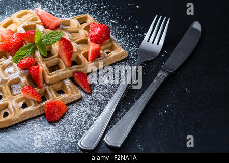 Hausgemachte Waffeln mit frischen Erdbeeren (auf dunklem Hintergrund) Stockfoto