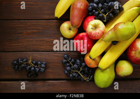 verschiedene Früchte (Äpfel, Birnen, Bananen, Trauben) auf einem hölzernen Hintergrund Stockfoto