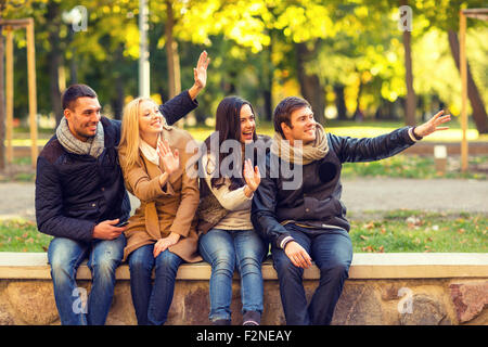 Gruppe von lächelnden Freunde winken Hände im Stadtpark Stockfoto