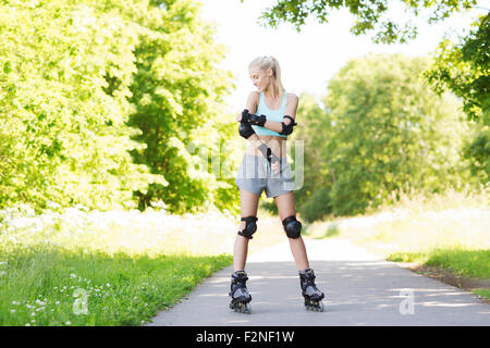 glückliche junge Frau in Rollschuhe fahren im freien Stockfoto