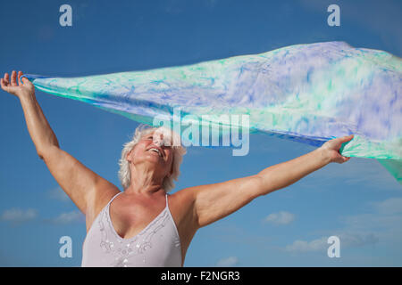 Ältere Frau kaukasischen halten Stoff im Wind unter blauem Himmel Stockfoto