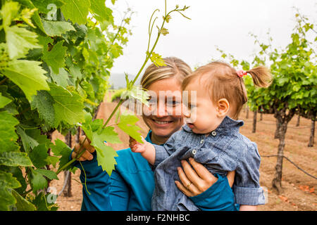 Kaukasische Mutter und Tochter bewundern Rebe im Weinberg Stockfoto