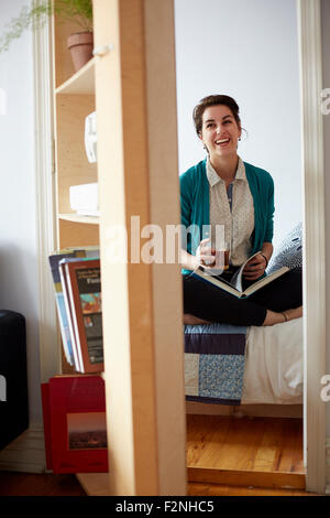 Frau, trinken Tee und lesen im Schlafzimmer Stockfoto