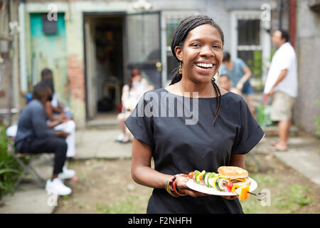 Afroamerikanische Frau Essen im Hinterhof Grill