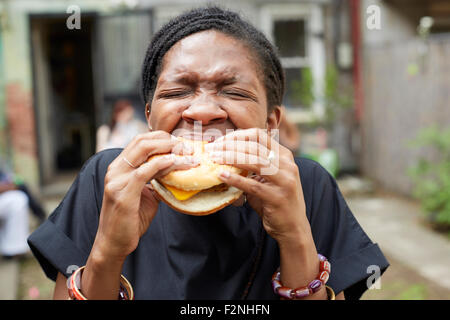 Afroamerikanische Frau Essen im Hinterhof Grill Stockfoto