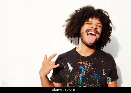 Gemischte Rassen Mann machen ein Gesicht und Rock-Handgeste Stockfoto