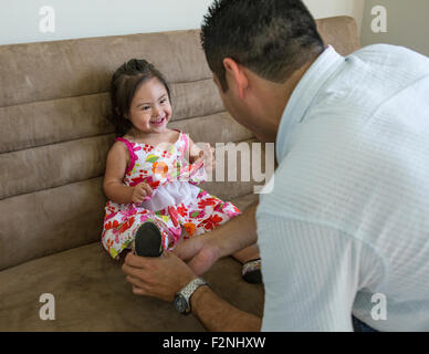 Hispanische Vater hilft Tochter Schuhe anziehen Stockfoto