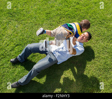 Erhöhte Ansicht der hispanischen Vater und Sohn spielen auf Rasen Stockfoto