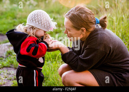 Kaukasische Mutter und Tochter spielen mit Küken im Garten Stockfoto