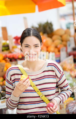 Hispanic Frau essen Obst am Bauernmarkt Stockfoto