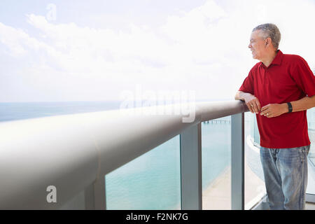 Älterer schwarzer Mann mit Blick auf das Meer vom Balkon Stockfoto