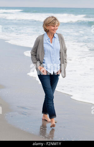 Lächelnde Frau kaukasischen zu Fuß am Strand Stockfoto