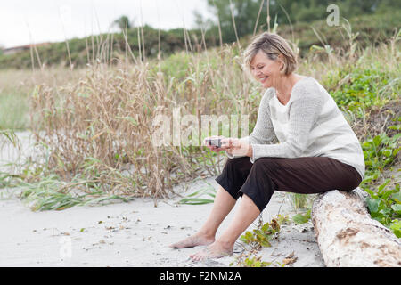 Kaukasische Frau mit Handy am Strand Stockfoto