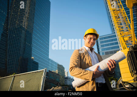 Gemischte Rassen Architekten halten Blaupausen auf Baustelle Stockfoto