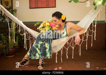 Frau riechen Blumenstrauß in Hängematte Stockfoto