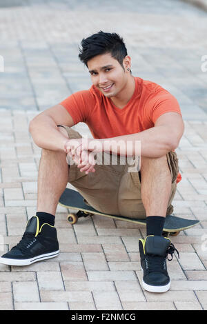 Gemischte Rassen Mann sitzt auf skateboard Stockfoto