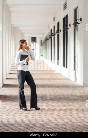 Kaukasische Geschäftsfrau, reden über Handy im Flur Stockfoto