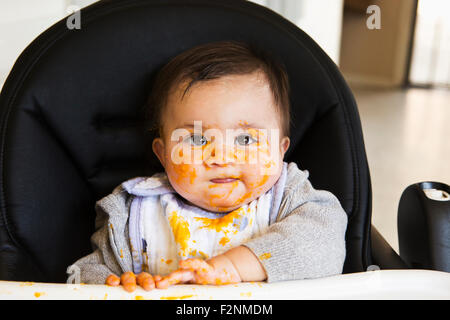 Chaotisch Mischlinge Baby Essen im Hochstuhl Stockfoto