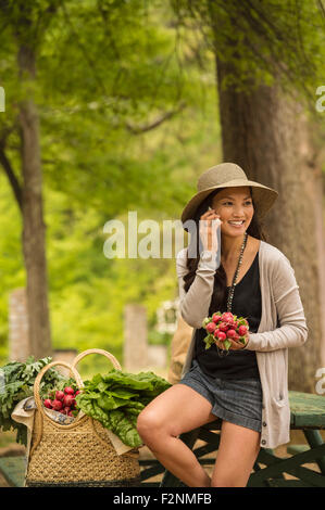 Asiatische Frau am Handy auf Picknick-Tisch Stockfoto