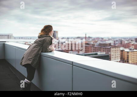 Kaukasische Frau auf städtischen Dach bewundern Stadtbild Stockfoto