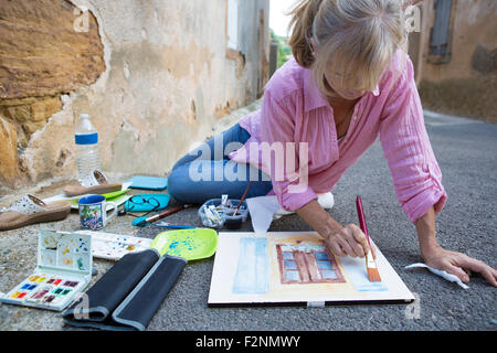 Kaukasische Frau malt auf Beton Boden Stockfoto