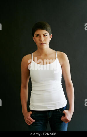 Hispanic Frau mit Daumen in Taschen Stockfoto
