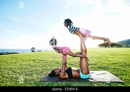 Mutter hält Kinder auf Yoga-Matte im park Stockfoto