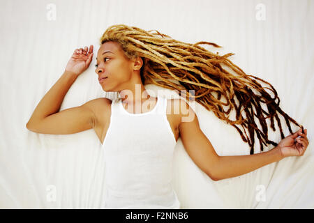 Schwarze Frau mit Dreadlocks auf Bett Stockfoto