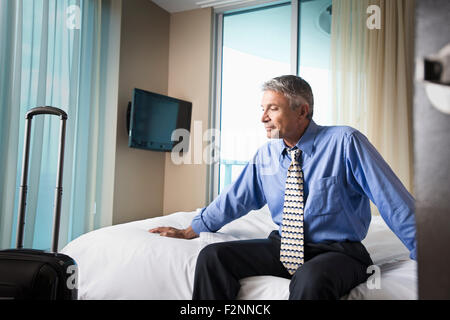 Kaukasische Geschäftsmann sitzt auf Hotelbett Stockfoto