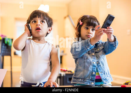 Bruder und Schwester spielen mit Handy und Fernbedienung Stockfoto