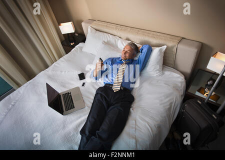 Kaukasische Geschäftsmann mit Handy auf Hotelbett Stockfoto