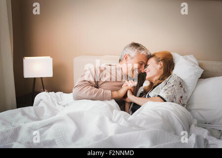 Lächelnde paar halten die Hände auf Bett Stockfoto
