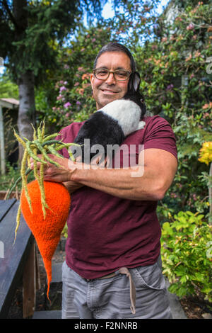 Gemischte Rassen Mann tragenden Kaninchen und gestrickte Karotte Stockfoto