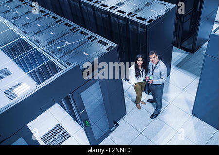 Erhöhte Ansicht von Technikern, die lächelnd im Serverraum Stockfoto