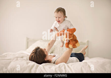 Kaukasische Mutter mit Baby im Bett spielen Stockfoto