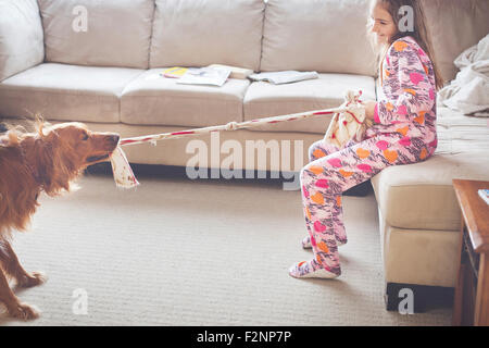 Kaukasische Mädchen spielen mit Hund im Wohnzimmer Stockfoto