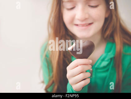 Kaukasische Mädchen Herzform Schokolade essen Stockfoto