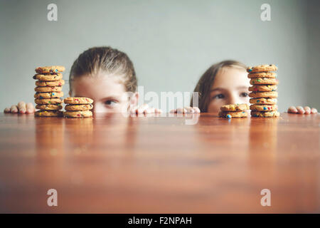 Kaukasische Mädchen starrte auf Cookies auf Tisch Stockfoto