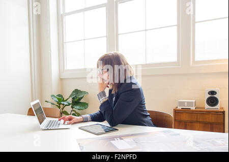 Geschäftsfrau mit Laptop am Schreibtisch im Büro Stockfoto